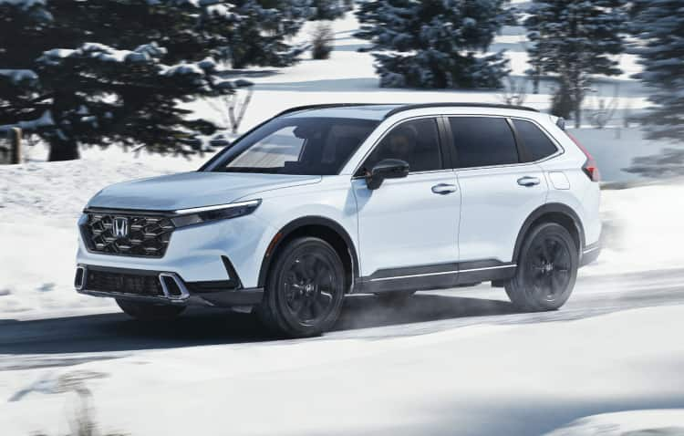 Front passenger-side view of the 2022 Honda CR-V Touring in Radiant Red Metallic with Honda Genuine Accessories, driving in an urban environment.