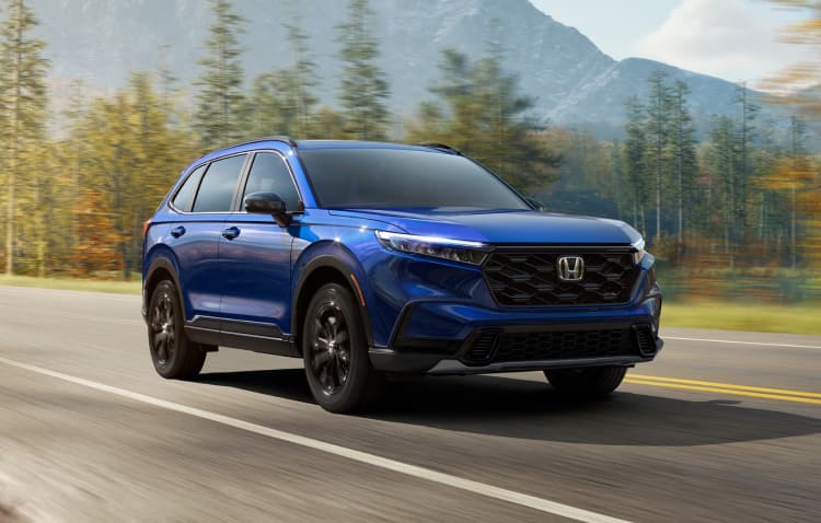 Passenger-side profile view of the 2022 Honda CR-V Touring in Sonic Gray Pearl, driving in an urban environment at night.