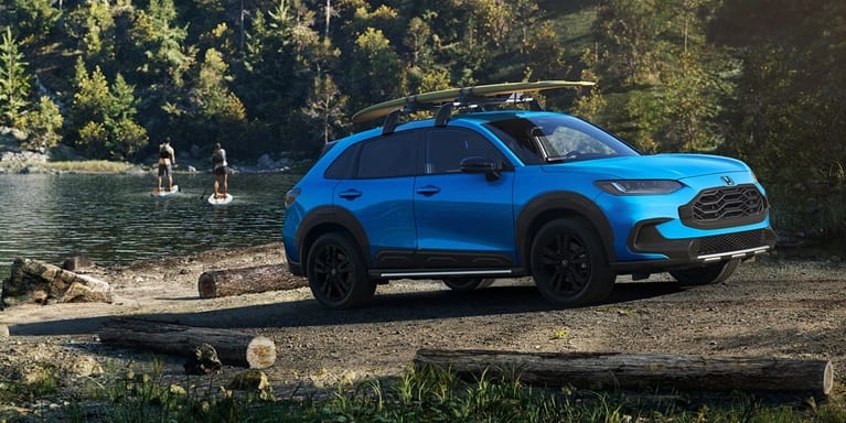 2027 Honda HR-V Sport in Boost Blue Pearl profile view parked near a lake with paddleboarders (Subcompact Crossover SUV).